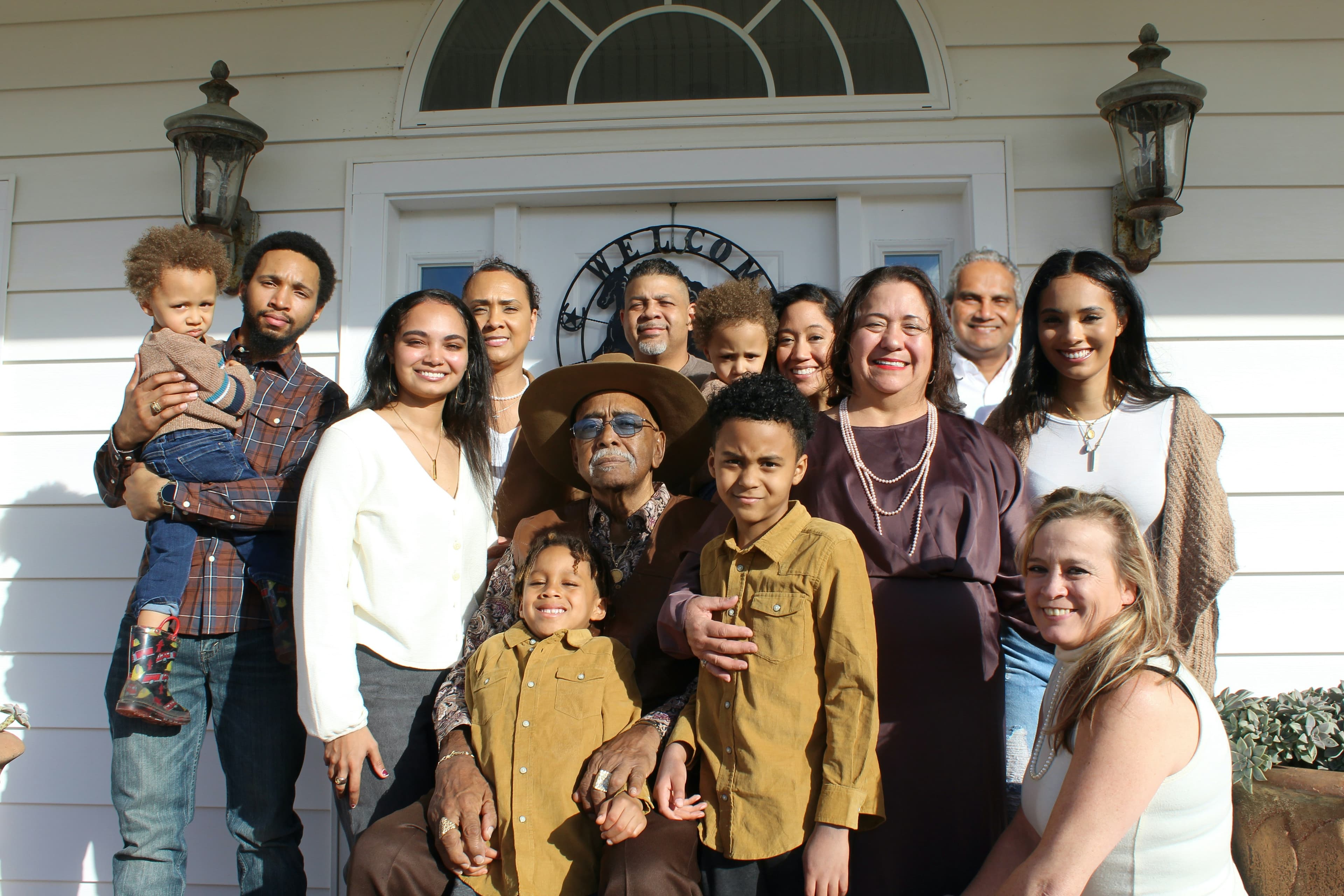 A photo of an extended family posing together in front of a white house.